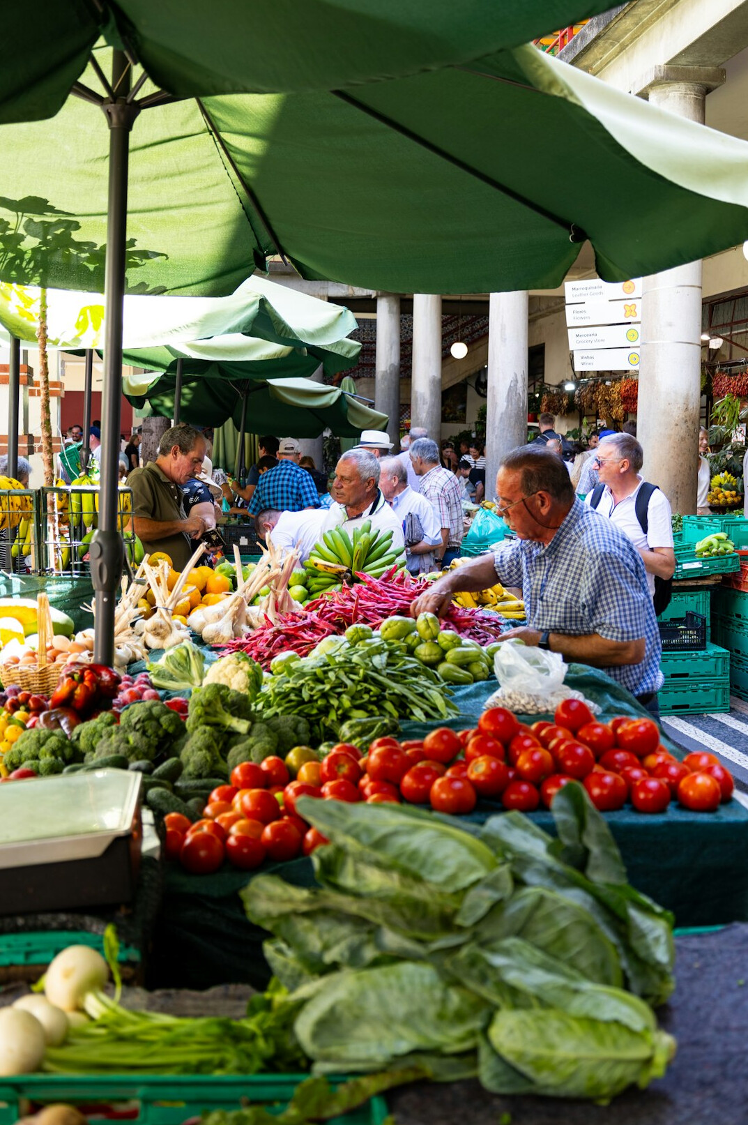 Busy outdoor local market stall with vegetables and sellers